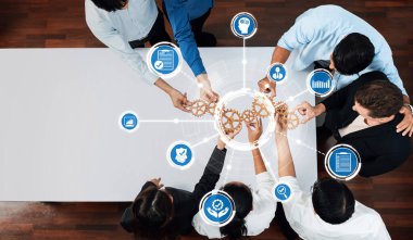 Dinamik bir ekip bir strateji oturumunda fikir paylaşımı yaparak yenilikçiliği ve etkili problem çözmeyi sembolize etmek için teknoloji simgeleri ve vitesleri kullanır. Dostluk