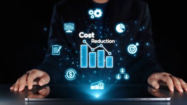 Bir işadamı dizüstü bilgisayarın önünde oturmuş, maliyet azaltma, finans stratejileri ve işyerindeki dijital yenilikleri temsil eden parlak simgeler ve grafiklerle uğraşıyor. Dörtgen