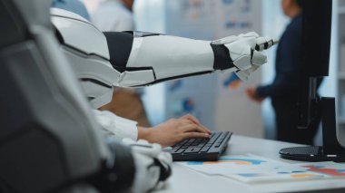 Modern bir ofiste bilgisayar klavyesine yazıp ileri teknoloji ve çalışma alanı dinamiklerini eylem halinde gösteren gelecekçi robot kolunun yakın çekimi. Noogenesis