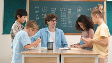 Zeki öğretmen, çeşitli çocuklar sınıf çalışması yapmak için birlikte çalışırken farklı çocukların zihin haritası çizdiği fikri açıklıyor. Çekici eğitmen öğretmek ve çalışmak hakkında konuşmak. Pedagoji.