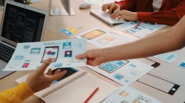 Mobil uygulama için kullanıcı arayüzü prototipini ofis çalışanlarına sunan harika bir şirket çalışanı. UX UI tasarımcısı kağıt üzerinde simge tasarımının işlevini açıklıyor. Sinerjik