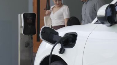 İlerici ebeveynler kızlarını okuldan alırken elektrikli araba ve yenilenebilir enerji kavramını kullandılar, evdeki EV otomobil için şarj istasyonu. Alternatif eko taşımacılığı.