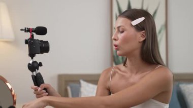 Sosyal medya için güzellik ve kozmetik video içeriği hazırlayan genç bir kadın. Güzellik blogcusu kameraya gülümserken seyircilere ve takipçilere güzellik bakımını gösteriyor. Düzenle