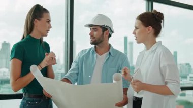 Profesyonel mimar mühendis ekibi konuşuyor, paylaşıyor, tasarım hakkında beyin fırtınası yapıyor. Yönetici planı dinlerken genç mimar plan yapıyor. İzleme