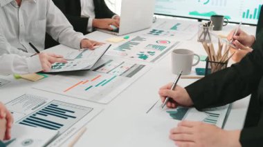 Çeşitli bir iş ekibi modern bir ofiste işbirliği içinde, finansal raporları analiz ediyor ve stratejileri geliştirmek ve projelerinde başarıyı yönlendirmek için veri içgörülerini tartışıyor. SACTR