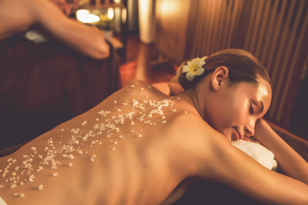 Пара клиентов, проводящих пилинг в роскошном спа-салоне с теплым свечой окружающей среды. Косметическое лечение бальзамическим скрабом в Health spa scrub. Quiescent