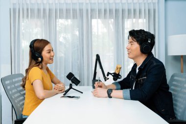 Gülümseyen radyo etkili sunucusu kulaklık takıyor kadın konuşmacı ile röportaj yapıyor sosyal medya internet sitesinden dinleyicilere bilgi paylaşıyor stüdyo kaydında sabah canlı yayın kanalı. İnfobahn.