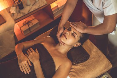 Beyaz kadın stres önleyici kafa masajı yapmaktan ve lüks otel veya otelde sıcak mum ışığında yüz güzelliği eğlencesi yapmaktan zevk alıyor. Sessiz.