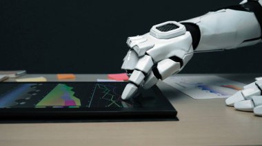 Dokunmatik ekran arayüzüne bağlanan, renkli grafikler ve veriler gösteren, gelişmiş teknolojiyi ve modern çalışma alanı yeniliğini sembolize eden robotik bir elin yakın çekimi.