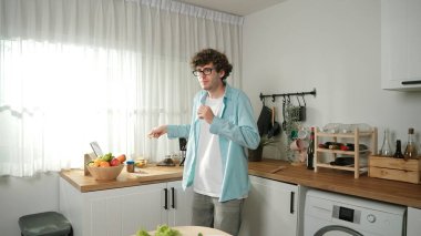 Mutlu baba yemek pişirirken müziğe geçiyor ve modern mutfakta öğle yemeği hazırlıyor. Aktif baba, sebze ve mutfak gereçleri ile çevrili sağlıklı yemek ya da salata yaparken şarkıyla dans ediyor. Pedagoji.