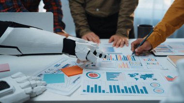 Robotik bir kol modern ofis ortamında profesyonellere yardımcı olurken, iş dünyası verilerini ve stratejilerini analiz ederken takım çalışmasını ve yeniliğini geliştirmektedir.