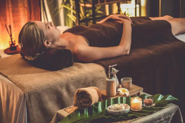 Aromaterapi masajı ambiyansı ya da spa salonu kompozisyon düzeneği bulanık kadınlara odaklı dekor mumları ve spa aksesuarları ile tatil köyü veya otel arka planında keyifli aroma spa masajı yapan. Sessiz.