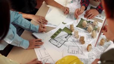 Mimari belge, ölçüm aracı ve ahşap blokların modern ofiste etrafa saçıldığı bir masa üzerinde yapı inşaatı ile ilgili mimar ve güvenlik mühendisi tartışması. Tanımlama.