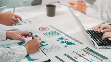 Çeşitli bir ekip, ortak bir toplantıya katılarak, verileri analiz eder ve parlak bir ofis masasında tablolar ve dijital cihazlarla iş büyümesi için strateji oluşturur. SACTR