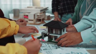 Mimarlar ve tasarımcılardan oluşan çeşitli bir grup, parlak bir ofiste, projeler, 3D modeller ve yaratıcı fikirlerle kavramları oluşturmak için tutkuyla çalışıyor. SACTR