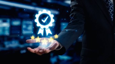 Bir işadamı, kalite güvencesi ve müşteri memnuniyetini simgeleyen dijital bir rozet sunar. Bu görüntü modern kurumsal değerleri yakalıyor, başarıyı ve güveni vurguluyor. Dörtgen