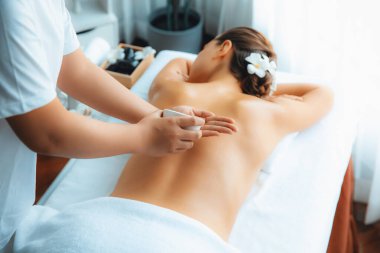 Masör elleri kadının sırtına aroma yağı döküyor. Masözler lüks otellerdeki kaplıca salonundaki müşteriler için yağ masajı prosedürü hazırlıyorlar. Aroma yağı vücut masajı konsepti. Sessiz.