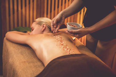 Lüks spa salonlarında sıcak mum ışığında cilt bakımı yaptıran kadın müşteri. Sağlık Spa vücut fırçasında tuz temizleme güzellik tedavisi. Sessiz.