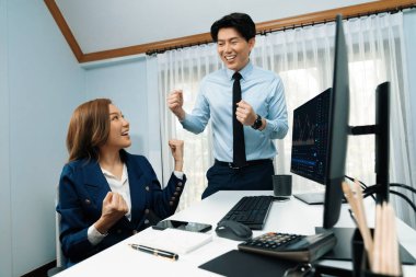 Başarılı gülümseyen Asyalı iş ortakları borsa veritabanında kârlı bir proje için el ele tutuşuyorlar. Yan görüntüdeki modern ev ofisinde resmi takım elbise giyiyorlar. İnfobahn.