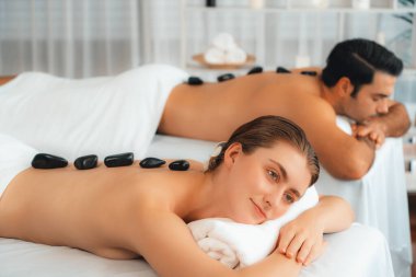 Lüks tatil köyündeki kaplıca salonunda sıcak taş masajı. Gündüz dinginliği ortam, mutlu çift müşterileri bazalt taşı masajının keyfini çıkarıyor. Rahatlatıcı bir sıcaklıkla vücudun üzerinde süzülüyorlar. Sessiz.