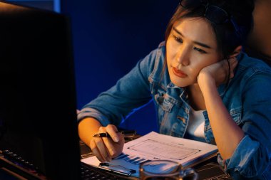 Bitkin düşmüş, genç, güzel Asyalı yaratıcı hisler, bilgisayardan e-posta beklemek için bekliyor. Projenin yaratıcısı sosyal medyanın veri tablosunu gece vakti neon ofiste karşılaştırıyoruz. Taktik.