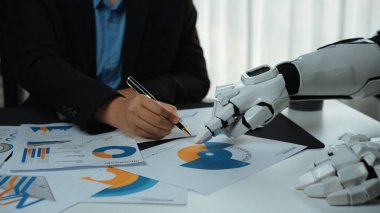 Bir insan el yazısı, teknolojinin iş uygulamalarına entegrasyonunu ve bunun takım çalışması ve verimliliği üzerindeki etkisini yansıtan robotik bir elin yanında notlar da yazar.