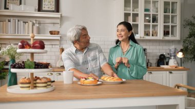 Büyükannem kahvaltısını sunarken, gülümseyen büyükbaba masada oturuyor. Yaşlı çift konuşuyor ve birlikte vakit geçiriyorlar ya da birlikte destek oluyorlar. Sağlıklı ilişki kavramı. Myrmidon.