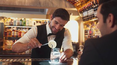 Akıllı barmen, lüks bir tezgahta arkadaşını beklerken limonlu cin kokteyli ikram ediyor. Barmen, canlı gece hayatı parti atmosferinde mükemmel hizmet veriyor. Vinosity.