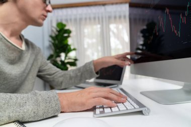 Bilgisayar ve dizüstü bilgisayarı kullanarak, çalışma masasındaki dinamik artırılmış borsa grafiğinin en yüksek kar değerini araştıran bir tüccar, modern ofisteki ekrandaki döviz kuru değerini analiz ediyor. Bireysel.