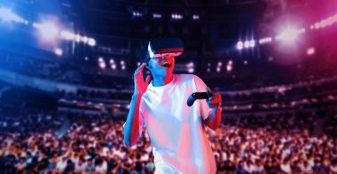 Yetişkinlerin elinde joystickle VR gözlükleri varken stadyumda arka planda bulanık oyunlar oynamaktan zevk alıyorlar. Afrikalı adam kontrol etmeyi ve artırılmış gerçeklik teknolojisini kullanmayı seviyor. Yaratıcılık.