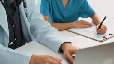 Hastane masasında birlikte çalışan ve tıbbi tedavi planlayan çeşitli profesyonel sağlık görevlileri. Takım çalışması başarılı hastalıklara ve hastalıklara yol açar. Ağır çekim. Katı.