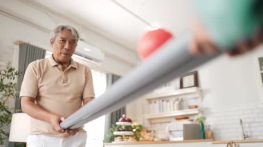 Yaşlı bir adam evde partneriyle top yuvarlama oyunu oynuyor, zihinsel ve fiziksel sağIık için el-göz koordinasyonu, odaklanma ve motor becerileri pratiği yapıyor. Sağlık hizmetleri konseptini engelliyor. Myrmidon.