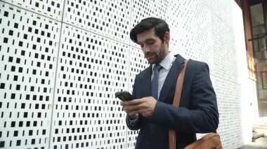 Akıllı iş adamı iş yatırımları için ekibi aramak için telefonu kullanıyor. İş planı, pazarlama stratejisi ya da çalışma hakkında konuşmak için akıllı telefonla konuşurken sokakta yürüyen bir yönetici. Sevinçli..