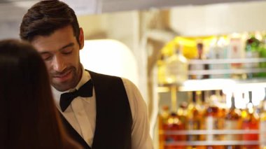 Güzel görünüşlü, zeki barmen dostu sohbet içecek tezgahında VIP müşteriyle konuşuyor. Profesyonel barmen kostümünde harika bir ilk izlenim bırakıyor. Vinosity.