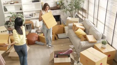 Taşınırken karton kutu taşırken birlikte dans eden mutlu çiftin üst görüntüsü. Çekici oda arkadaşı arkadaşına gösterirken kutudan bez toplarken müziğe yönelmiş. Yeniden yerleştirme. Myrmidon.