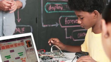 Şirin Afrikalı çocuk dizüstü bilgisayar gösterirken elektronik alet kullanmayı öğrenirken öğretmen de mühendislik komut yazmaktan bahsediyor. Araba modelini tamir etmek için çeşitli çocuk programları. Öğretim