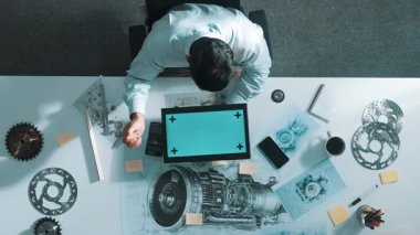 Profesyonel mühendis, türbin motoru veya jet motoru tasarımı ve çeşitli metal teçhizat dağılımı ile toplantı masasında yeşil ekranlı tablet üzerinde çalışırken telefona bakıyor. Hizalama.