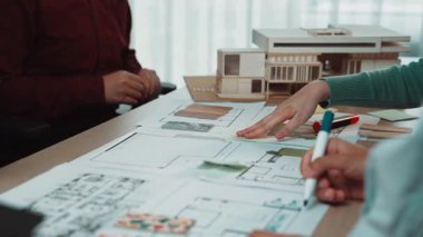 Bir grup bireyin mimari bir model üzerinde işbirliği yaptığı dinamik bir sahne. Çeşitli eller meşgul, modern bir çalışma alanında fikirler ve planlama tartışıyorlar. SACTR