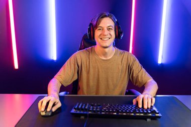 Kazanmak için çevrimiçi oyun oynayan akıllı flama makinesinin sunucu kanalı, neon ışıklı odada seçilen takım yarışması için izleyicilerle birlikte canlı yayında canlı yayında kulaklık takıyor. Bireysel.