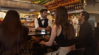 Gece kulübündeki lüks gece kulübünde, içki tezgahında çalışan akıllı barmen servisinde çift ya da arkadaş grubuyla gülen VIP müşterilere özel cin kokteyli servisi. Vinosity.