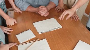 Kafkas öğretmeni ve çeşitli çocuklar başarılı bir projeyi kutlamak için el ele tutuşurken kağıt masaya saçıldı. Aşkı, şirketi, takım çalışmasını, birlikteliği ve birliği temsil et. Öğretim