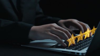 Dizüstü bilgisayarın klavyesinde yazı yazan ellerin yakın plan bir fotoğrafı, etrafında yüzen yıldızlar ve konuşma baloncukları var, çevrimiçi yorumlar ve geri bildirimlerin önemini gösteriyor. Dörtgen