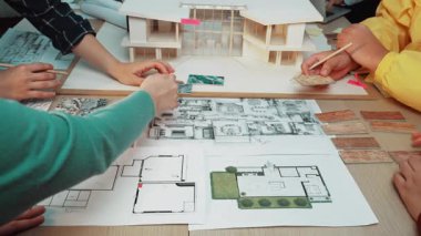 Çeşitli bireylerden oluşan bir grup modern bir yapı projesi için modeller ve çizimler üzerinde çalışarak ilham verici bir mimari tasarım oturumunda işbirliği yapmaktadır. SACTR