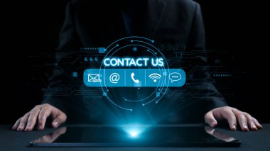 Takım elbiseli profesyonel bir işadamı, elektronik posta, telefon ve sohbet simgeleri de dahil olmak üzere iletişim seçeneklerini gösteren fütüristik bir dijital arayüzle etkileşime girer ve modern iletişimi önerir. Dörtgen