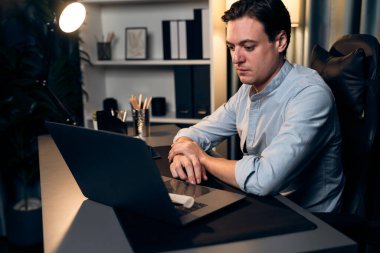 Akıllı iş adamı, gece vakti mavi perde arkasında iş hedefi olan finansal teknoloji veri raporlarını analiz etmek için veritabanı stoklarını araştırmak üzere dizüstü bilgisayarda uzaktan çalışıyor. Bireysel.