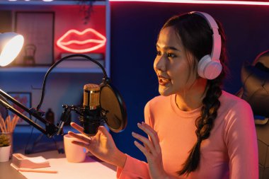 Geceleri podcast 'te olumlu konuşmalar yapan, pembe neon ışıklı modern stüdyoda sunum için dizüstü bilgisayar kullanan, gülümseyen, genç, güzel Asyalı bir etkileyiciydi. Taktik.