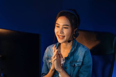 Sunucu kanalı Asyalı etkileyicisi canlı yayında konuşuyor. Sosyal medyada kulaklık takıyor, bilgisayar kaydı yapıyor, dinleyicileri selamlıyor ve Neon Modern Stüdyoları 'nda online olarak koçluk yapıyor. Taktik.