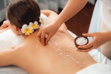 Lüks spa salonlarında sıcak mum ışığında cilt bakımı yaptıran kadın müşteri. Sağlık Spa vücut fırçasında tuz temizleme güzellik tedavisi. Sessiz.
