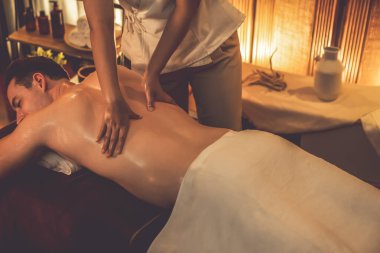 Beyaz erkek müşteri stres önleyici spa masajının keyfini çıkarıyor ve lüks otel ya da oteldeki ortam kaplıcalarında sıcak mum ışığında güzellik teniyle eğleniyor. Sessiz.