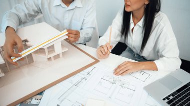 Profesyonel mühendis ev modelini tartartarken, yetenekli tasarımcı da planına yazar. Birlikte çalışmak, işbirliği, işbirliği. Yaratıcı tasarım ve takım çalışması konsepti. - Yakın çekim. Tertemiz.